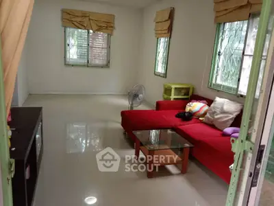 Spacious living room with red sofa and natural light, perfect for relaxation.