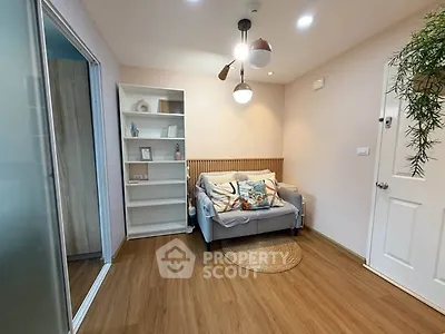 Cozy living room with modern decor and wooden flooring, featuring a comfortable sofa and stylish lighting.
