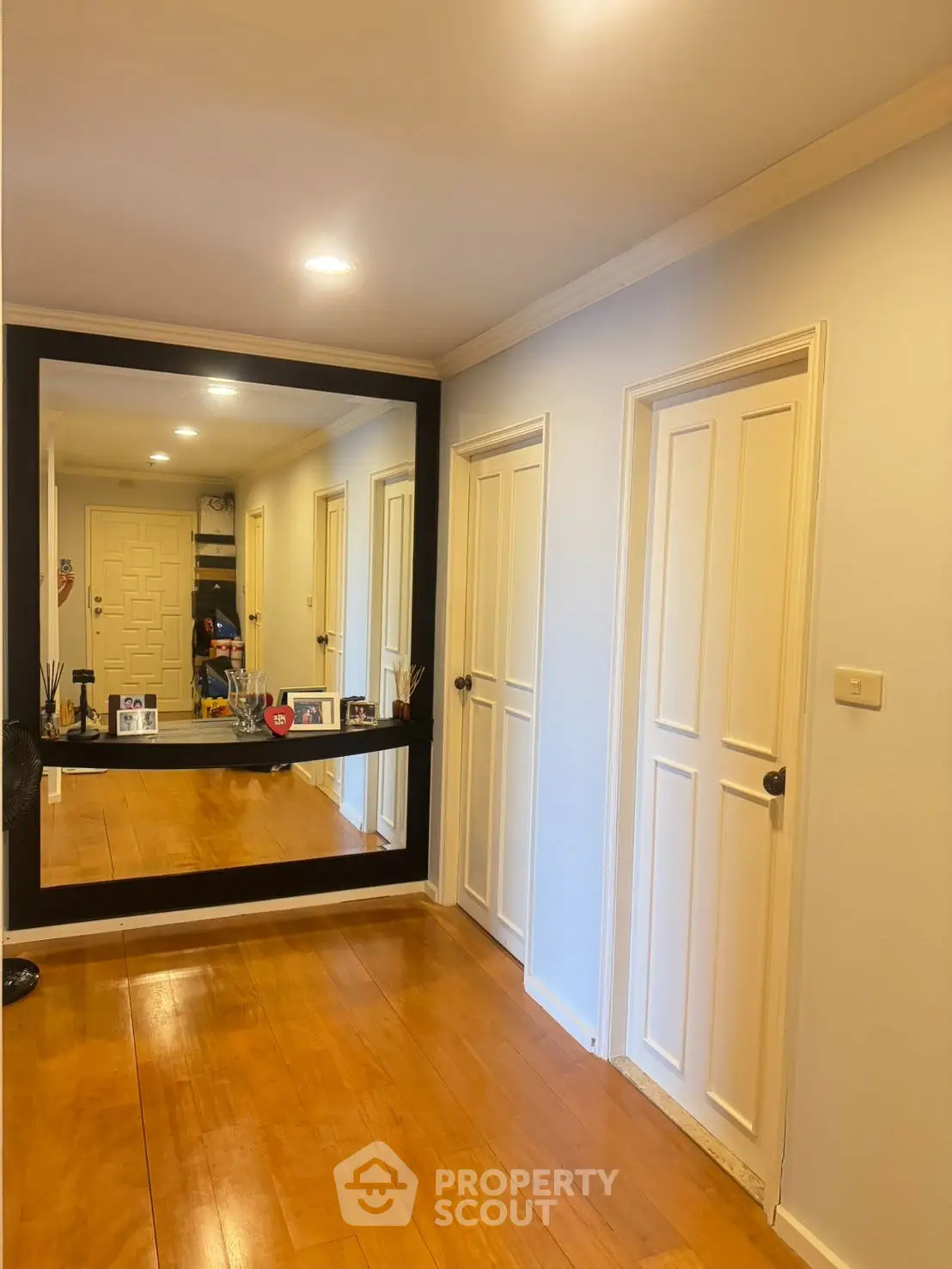 Spacious hallway with elegant wooden flooring and large mirror, enhancing the home's interior appeal.