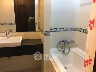 Modern bathroom with sleek sink and bathtub featuring stylish tile accents.