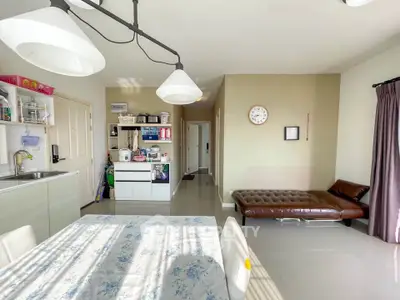 Spacious living room with modern decor and ample natural light, featuring a dining area and sleek furnishings.