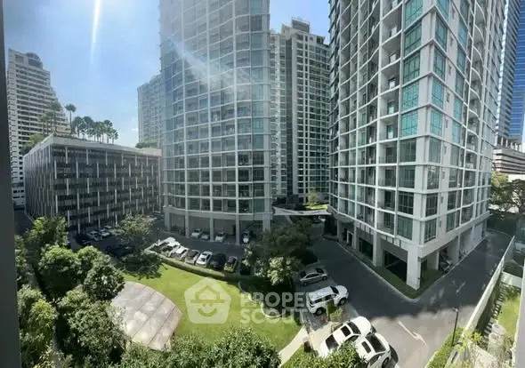 Modern high-rise residential buildings with lush green garden and parking area view.