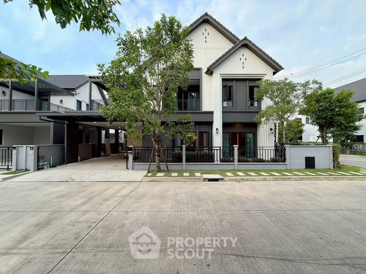Modern two-story house with sleek design and spacious driveway in suburban neighborhood.