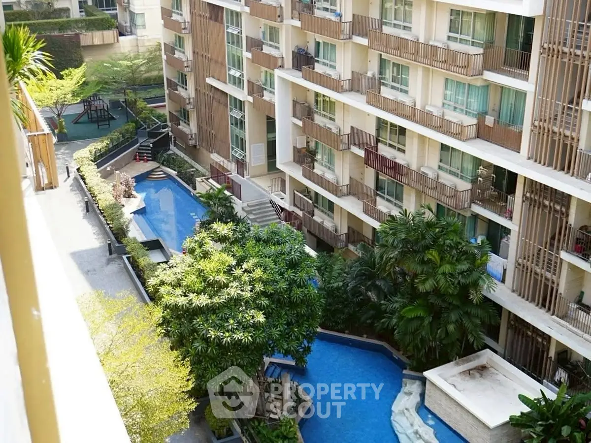Luxurious apartment complex with stunning pool and lush greenery view.