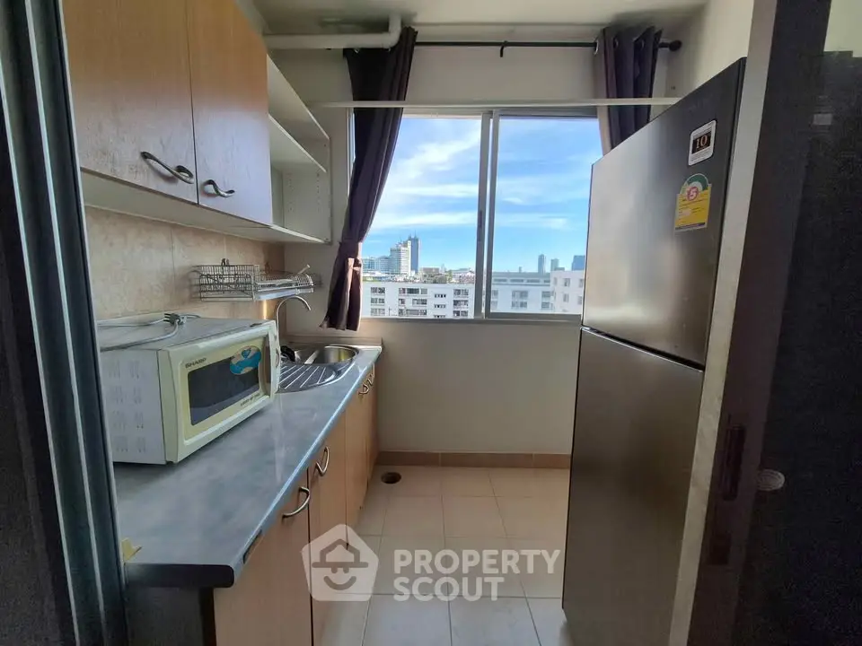 Compact kitchen with modern appliances and city view from window