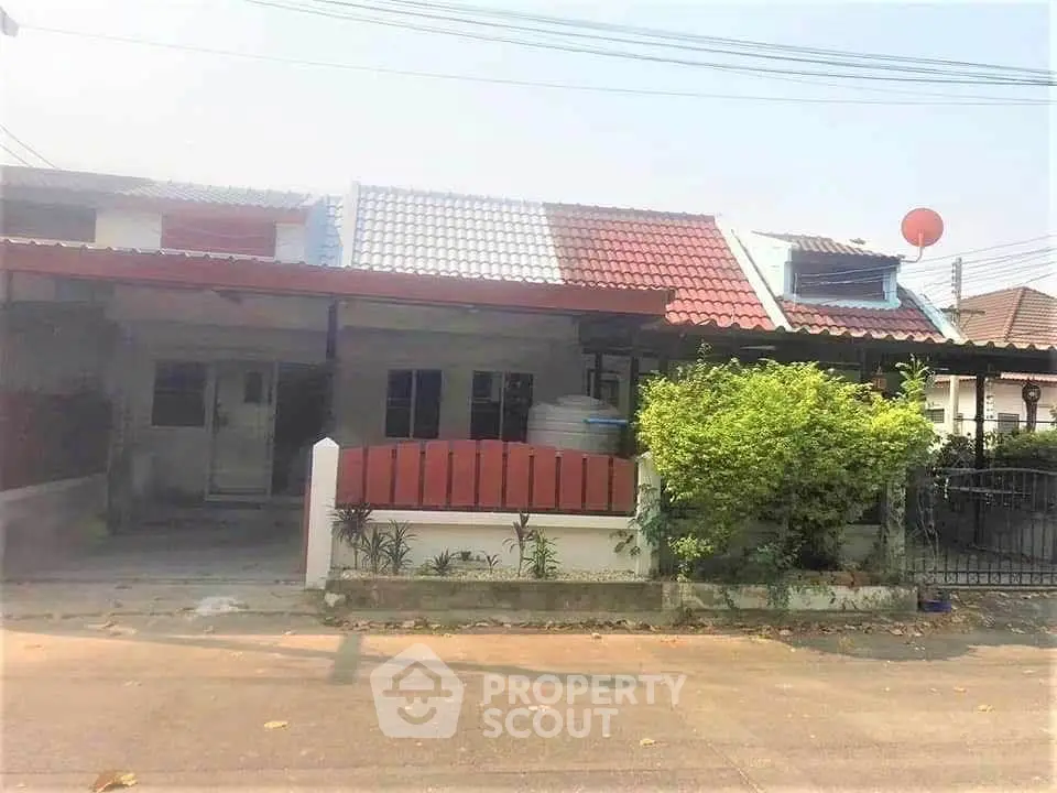 Charming single-story home with red-tiled roof and lush greenery in a peaceful neighborhood.