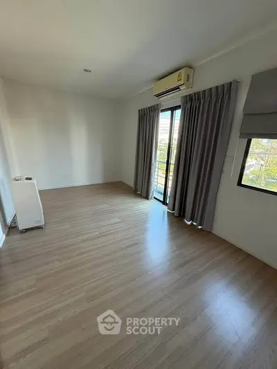 Spacious empty room with wooden flooring and large window, perfect for customization.