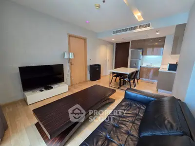 Modern living room with sleek furniture and open kitchen layout in a stylish apartment.