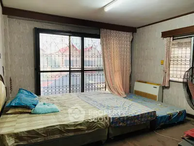 Cozy bedroom with large window and comfortable bedding in a charming home.