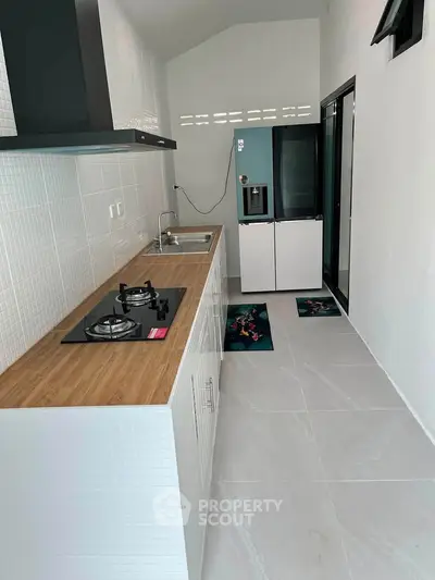 Modern kitchen with sleek design, gas stove, and wooden countertop in a compact layout.