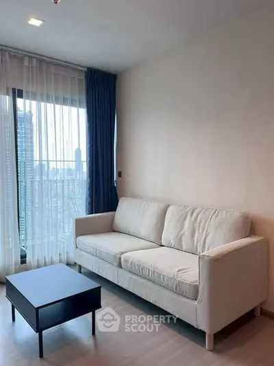 Modern living room with a cozy sofa and city view from the window.