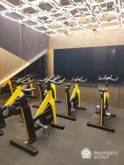 Modern gym with stylish lighting and yellow exercise bikes