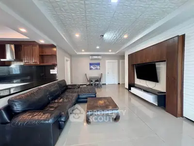 Spacious modern living room with leather sofa and wall-mounted TV