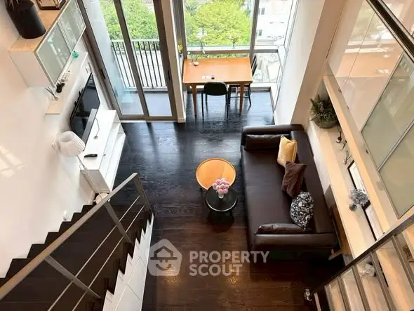Stunning modern loft with high ceilings, large windows, and a spacious living area overlooking a lush green view.