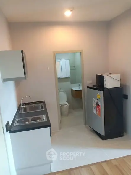 Compact kitchen with modern appliances and adjacent bathroom in cozy apartment.