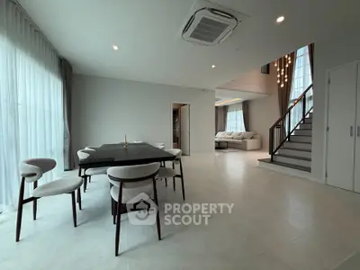 Spacious modern living and dining area with elegant staircase and natural light.