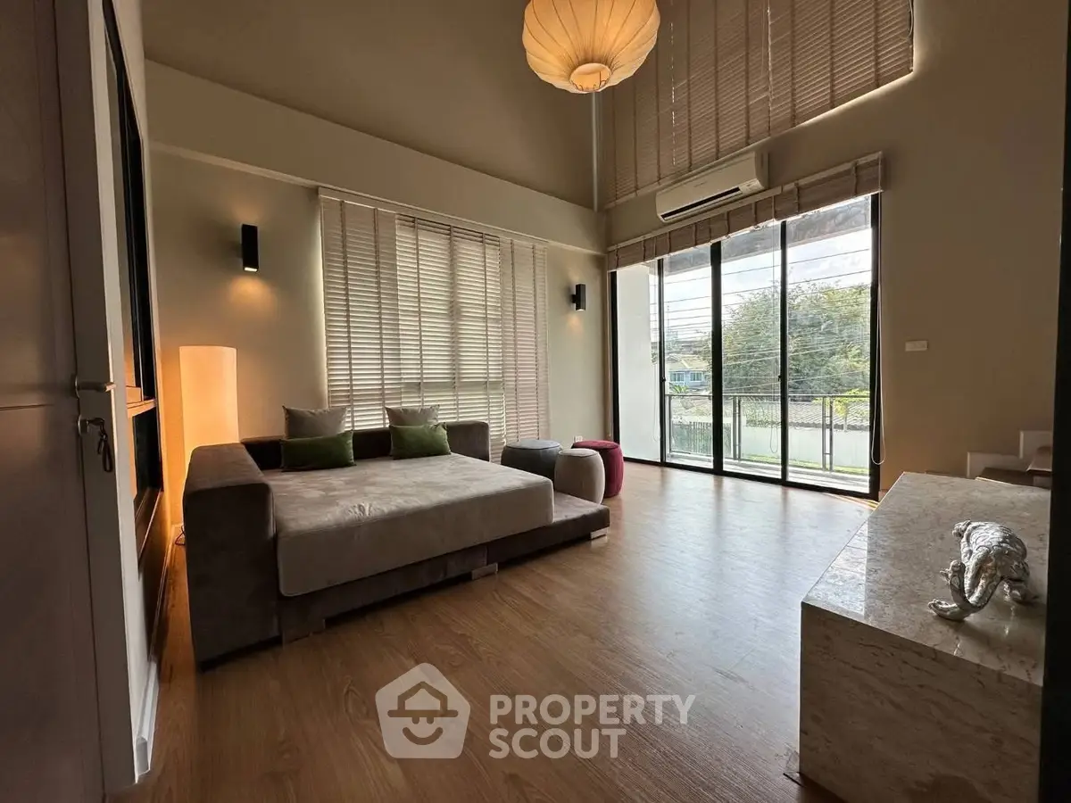 Spacious modern living room with large windows and stylish decor, perfect for relaxation and entertaining.