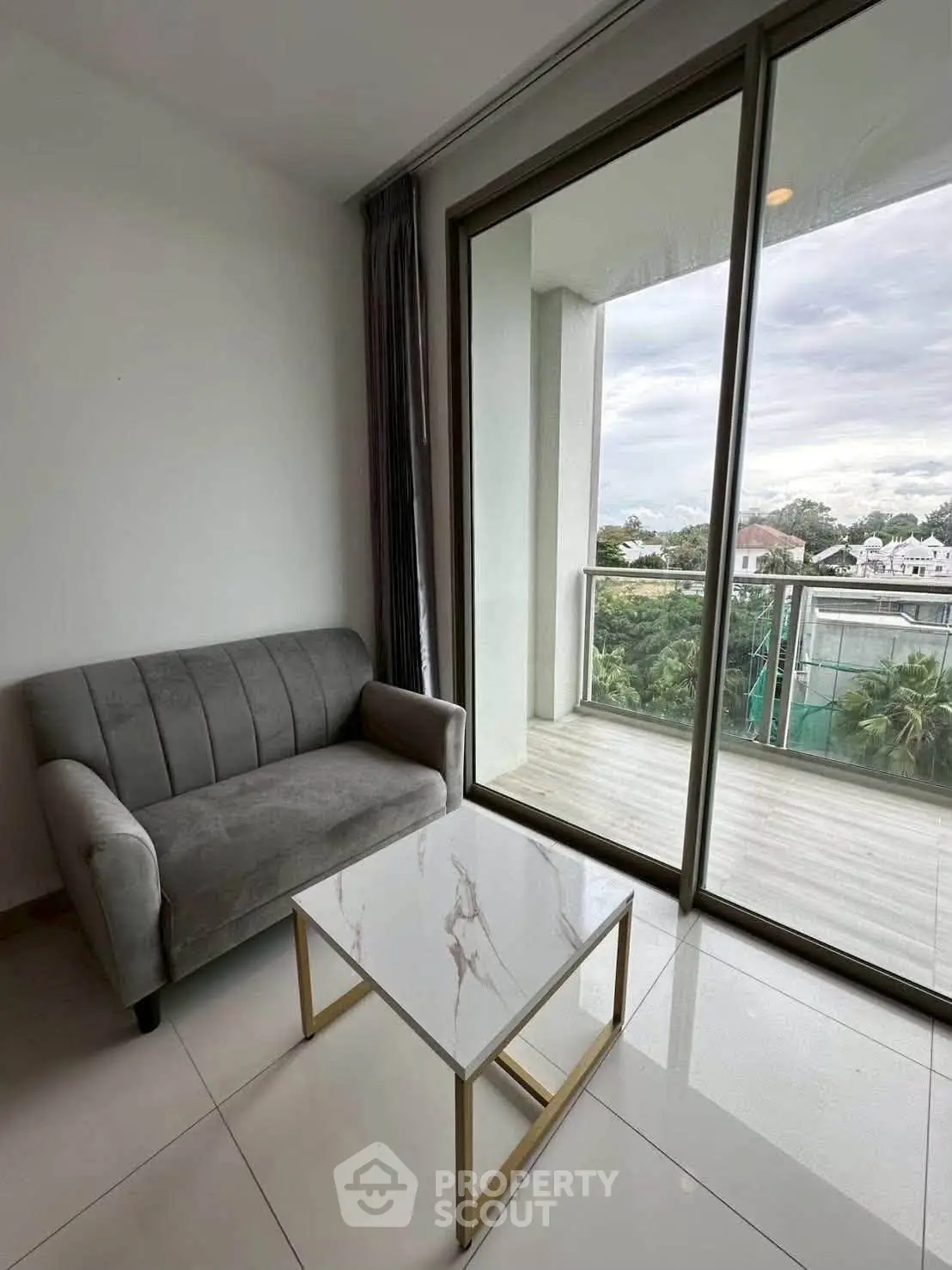 Modern living room with cozy sofa and elegant coffee table, featuring a large window with balcony view.