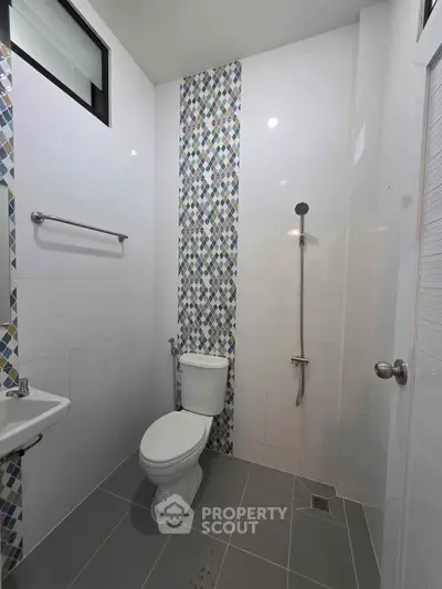 Modern bathroom with sleek design, featuring a toilet, shower, and stylish tile accents.
