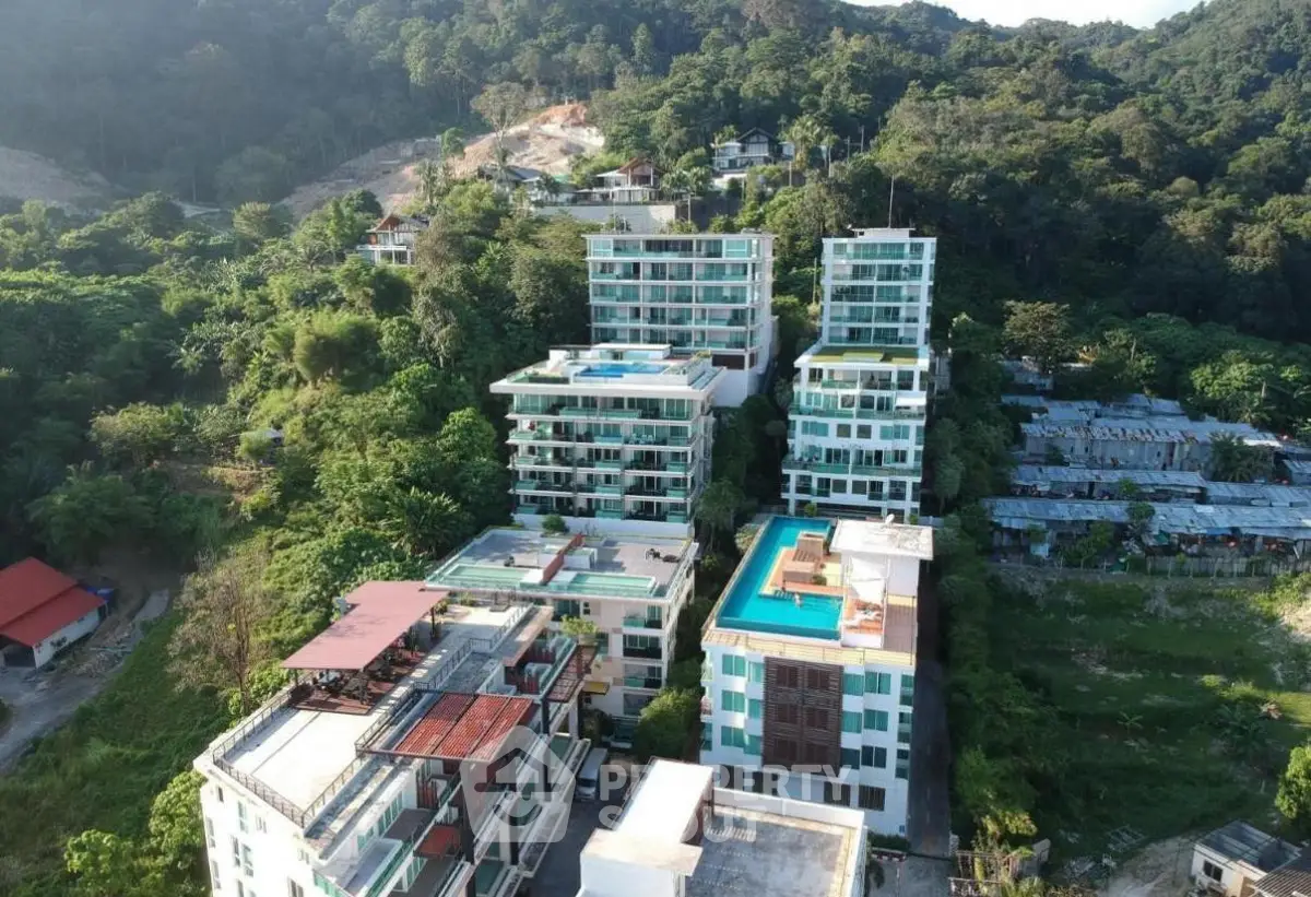 Aerial view of modern hillside apartment buildings surrounded by lush greenery and scenic landscape.