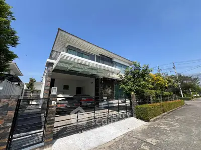 Modern two-story house with carport and lush greenery in a serene neighborhood.