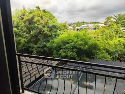 Charming balcony view with lush greenery and distant rooftops, perfect for nature lovers.
