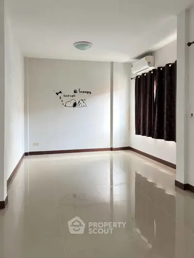 Spacious empty room with glossy tiled floor and wall art, perfect for customization.