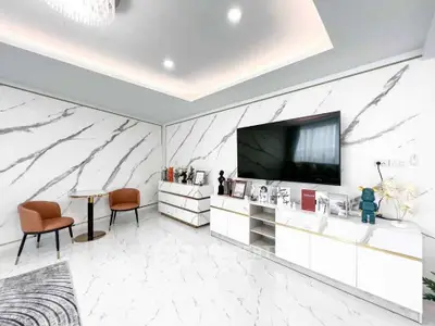 Luxurious modern living room with marble walls and floor, featuring a large TV and elegant furniture.