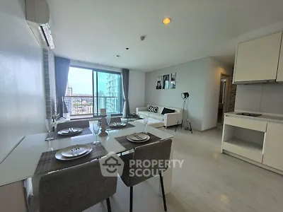 Modern open-plan living room with dining area and city view, featuring sleek furniture and large windows.