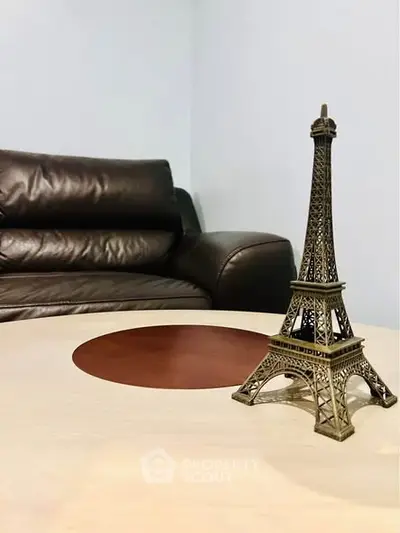 Cozy living room with leather sofa and decorative Eiffel Tower model on table.