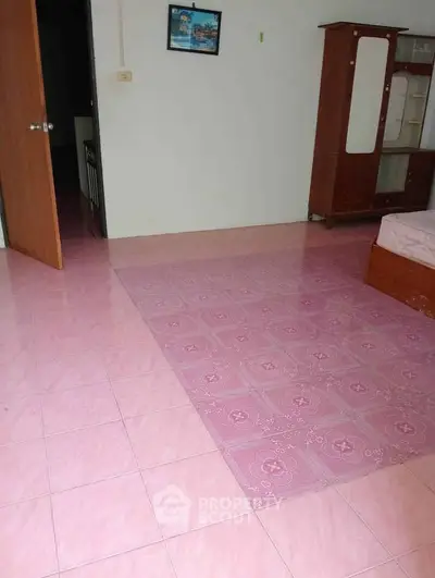 Spacious bedroom with pink tiled flooring and wooden furniture
