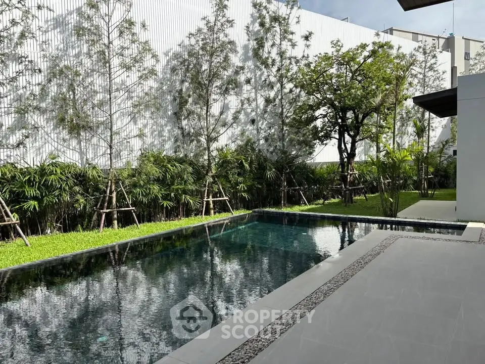 Luxurious modern poolside with lush greenery and sleek design, perfect for relaxation and entertainment.