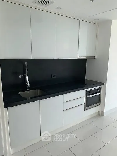 Modern kitchen with sleek cabinetry and built-in oven in a contemporary apartment.