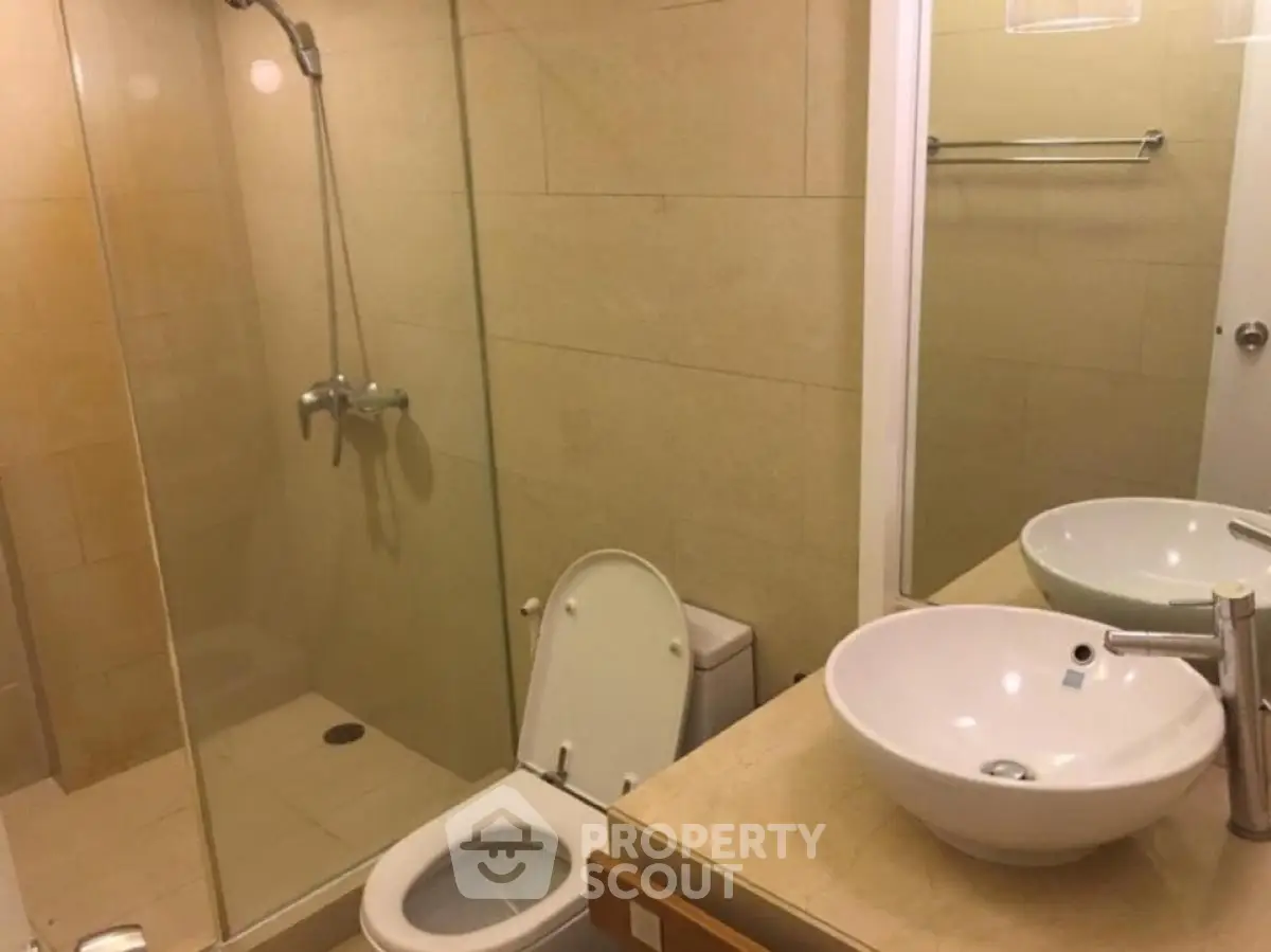 Modern bathroom with glass shower and dual sinks in a stylish real estate property.