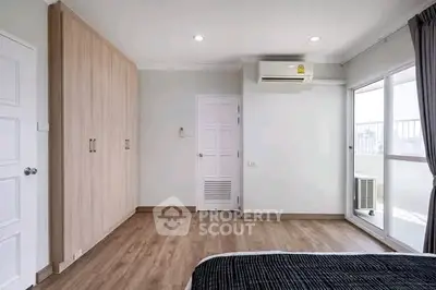 Modern bedroom with wooden flooring, built-in wardrobe, and balcony access.