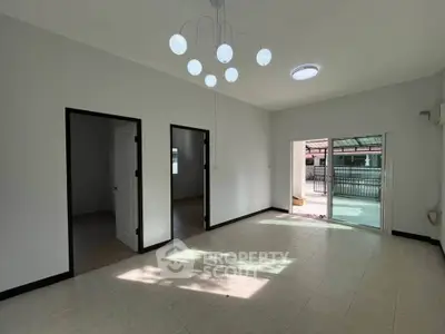 Spacious living room with modern lighting and access to a sunlit balcony, perfect for relaxation.