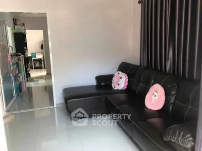 Cozy living room with modern black leather sectional sofa and plush pillows, perfect for relaxation.
