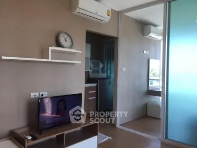Modern living room with TV, air conditioning, and open kitchen layout in a stylish apartment.