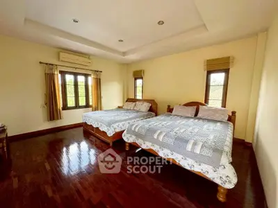 Spacious bedroom with two beds and wooden flooring in a cozy home