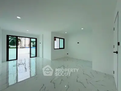Spacious modern living room with marble flooring and large windows overlooking a pool area.