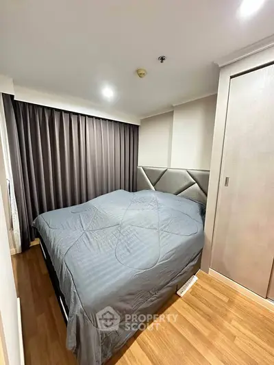 Cozy bedroom with modern decor and wooden flooring, featuring a large bed and elegant curtains.