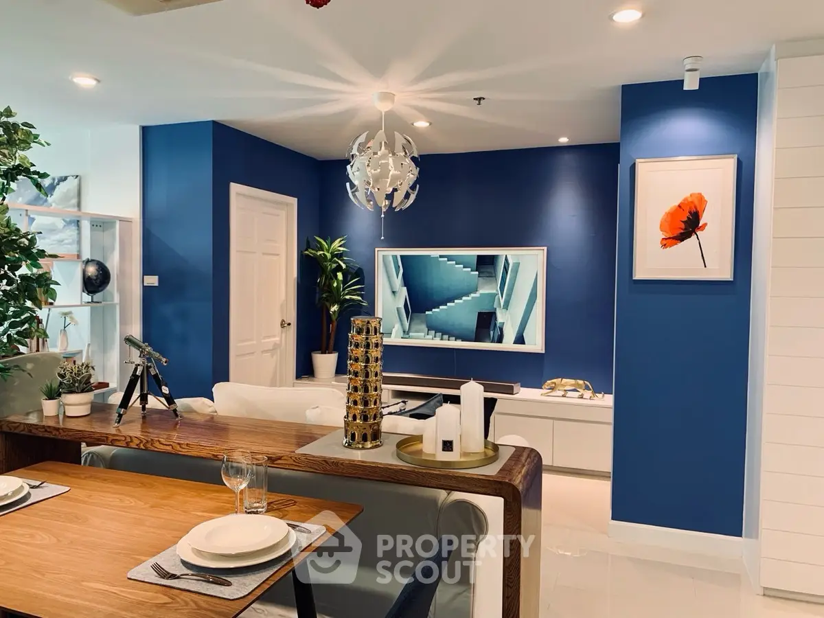 Modern living room with stylish decor and blue accent wall, featuring a sleek TV setup and elegant dining area.
