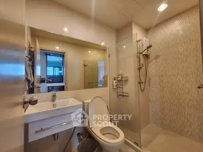Modern bathroom with glass shower and sleek fixtures in a contemporary apartment.