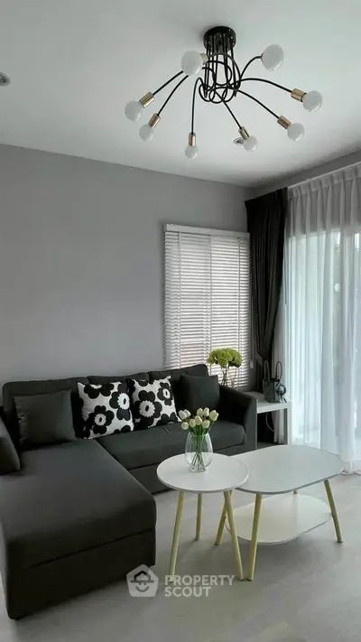 Modern living room with stylish chandelier and cozy sectional sofa.