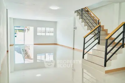 Spacious modern interior with glossy floors and stylish staircase, perfect for versatile living or office space.
