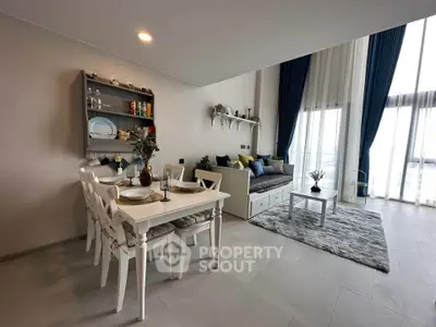 Modern living room with dining area, high ceilings, and large windows offering natural light.