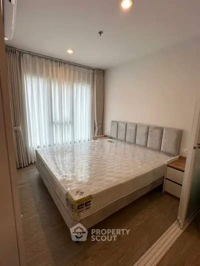 Cozy bedroom with large window and modern furnishings, perfect for relaxation.