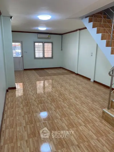 Spacious open-plan living area with tiled flooring and staircase, perfect for modern living.