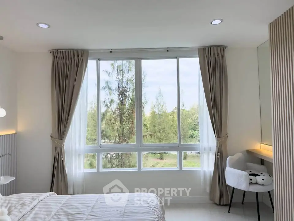 Bright bedroom with large window offering serene garden view, elegant curtains, and cozy decor.