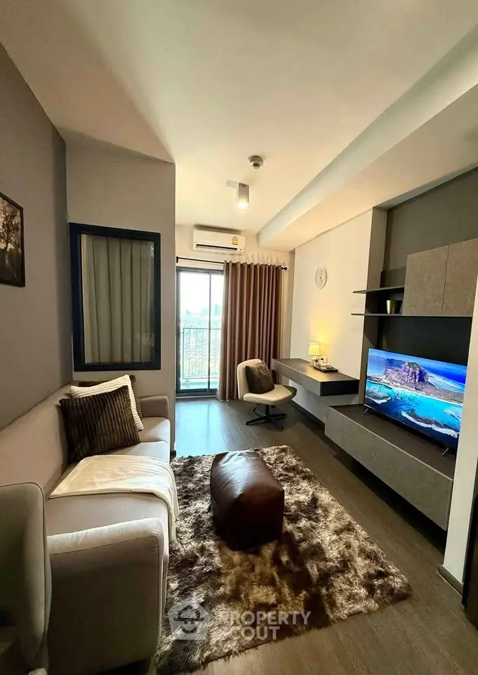 Modern living room with stylish decor and large TV, featuring cozy seating and elegant lighting.